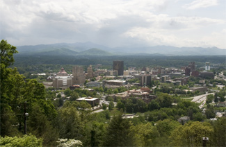 Photo of Asheville, North Carolina showing its buildings, city and currounding forests and hills, and  mountains
